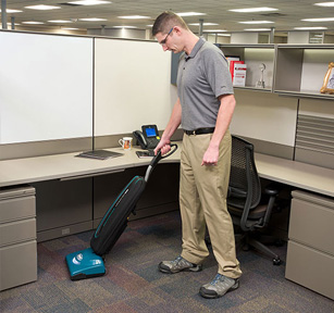 cleaning crew using tennant upright vacuum to clean office cubicle