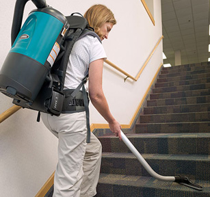 custodial staff using tennant backpack vacuum to clean office building carpeted stairs