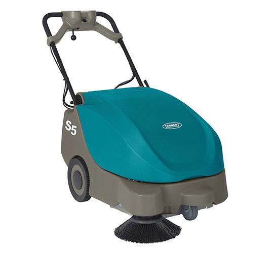 Uma trabalhadora efetua a manutenção de um pavimento de betão polido com uma auto lavadora.